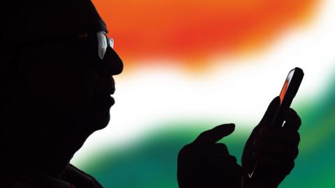 Silhouette of a senior Indian man using an mobile app - stock photo. 