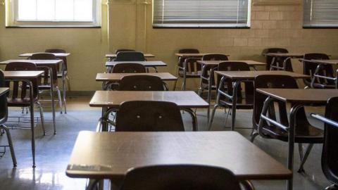 A row of tables and chairs inside a classroom.