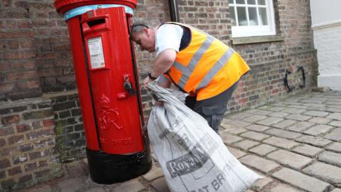 Postman empties letter box