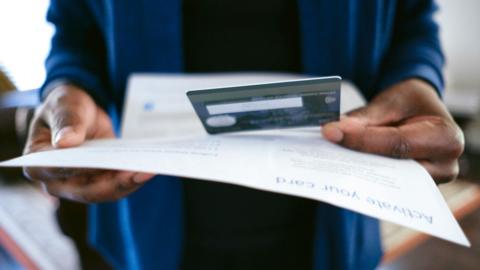 Close-up of unidentified woman opening mail containing new credit card