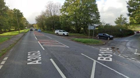 Google Street View of A3052 in Aylesbeare with cars travelling towards the camera and using a turn-off towards Exeter Airport