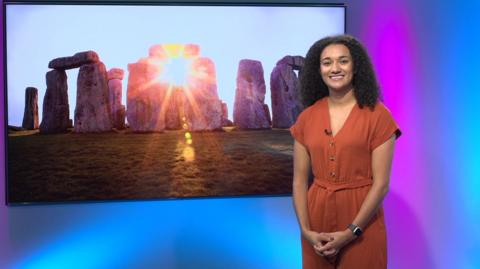 Nina in the studio with a picture of Stonehenge