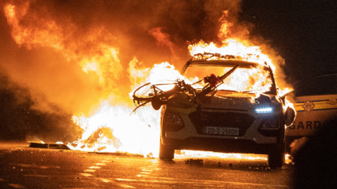 Police car alight in Dublin, flames visible all around