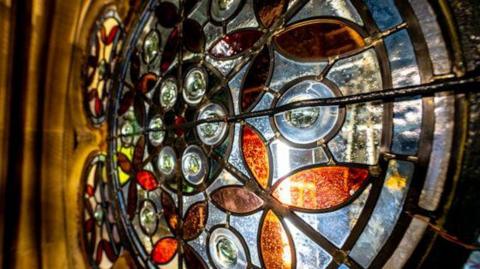 A stained glass windows featuring glass in the colours blue, yellow and green.