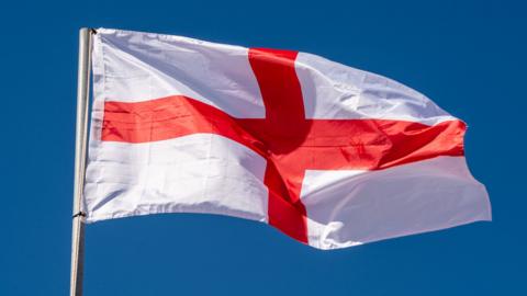Close up of English Flag waving against clean blue sky, isolated - stock photo