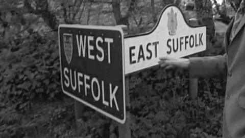 Signs back to back reading 'West Suffolk' and 'East Suffolk'