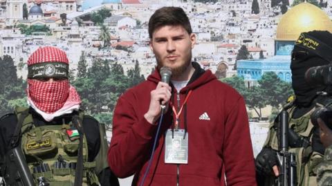 Masked Palestinian gunmen stand either side of Israeli hostage Sasha Troufanov during his release