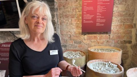 A woman with blond hair holding a clay pipe