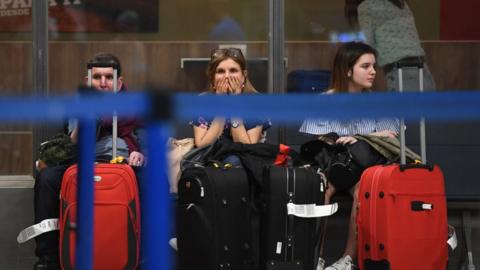 Passengers wait near airport check-in counters