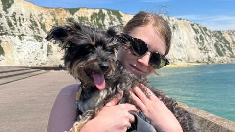 A woman holding her black dog