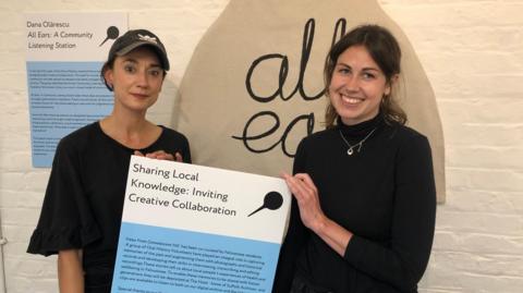 Natalie Pace and Jilly Roberts hold a poster as they stand inside Felixstowe museum