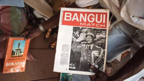 A souvenir seller shows the first issue of the weekly newspaper "Bangui Match" bearing the picture of Bokassa, in Bangui, 17 September 2019