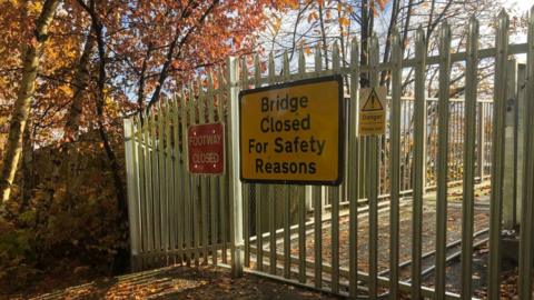 A sign on a gate that reads: bridge closed for safety concerns