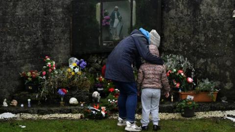 A mother and her daughter pay their respects at the Tuam graveyard where the bodies of 796 babies were uncovered