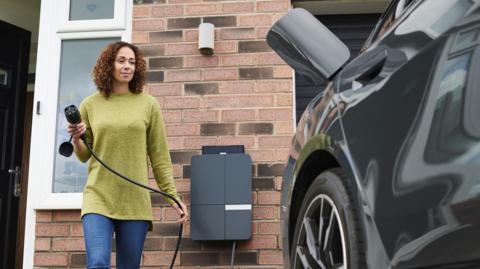 Woman charging an electric car outside her house