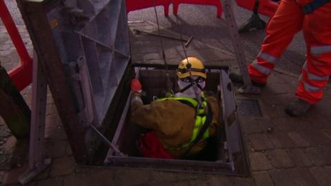 Worker being lowered into sewer