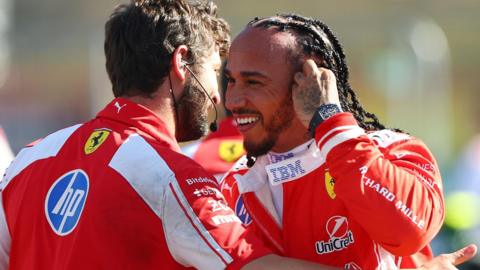 A smiling Lewis Hamilton is congratulated by a Ferrari team member after taking pole position for the British Grand Prix sprint race
