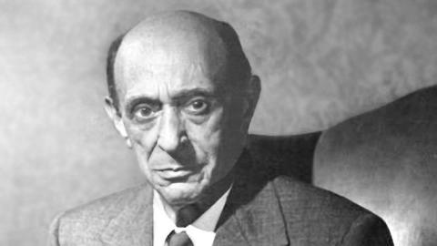 Black and white headshot portrait of Arnold Schoenberg from 1949. He is wearing a jacket and tie and is looking at the camera