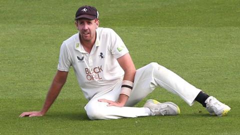 Kent pace bowler Matt Quinn sitting on the outfield during a County Championship game.