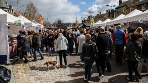 Crowds gathered at Bishop Auckland Food Festival. Food stalls line both sides of the street.