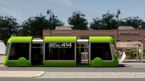 A mock image of a green coloured tram with the words Hemel to Harlow written on its side outside Hatfield station 