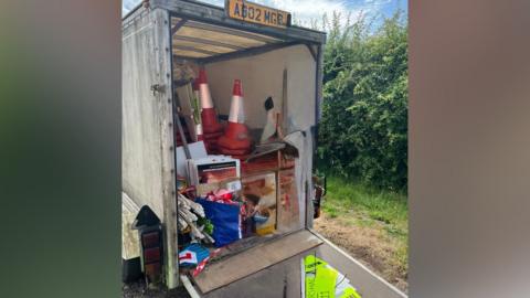 A view of a trailer packed with high vis jackets, cones and other kit used to stage a road race