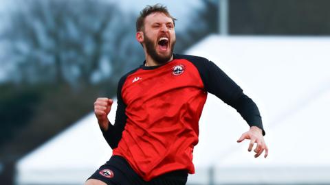 Tom Harrison of Truro City jumps into the air in celebration after scoring against Aveley 