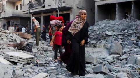 Palestinians inspect the site of an overnight Israeli strike on a house in Gaza City
