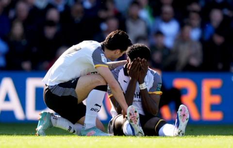 Derby's Patrick Agyemang with his hands over his face as he is consoled by a team-mate after suffering an injury