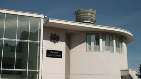 Exterior of Exeter Law Courts. It's a white building with a glass front on the left hand side.