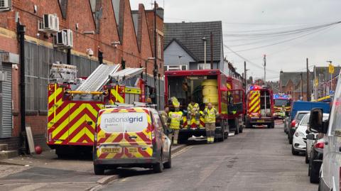 Fire engines parked up outside a red brick industrial building