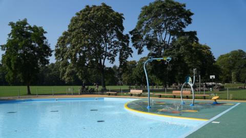 A splash park, with a large shallow area of water with a number of water play equipment