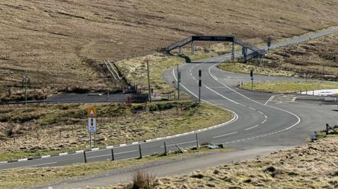 The road at the Bungalow, which snakes off in an S shape under a metal footbridge.