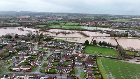 An areal shot of fields across Taunton covered by water. In the front of the shot are groups of houses.