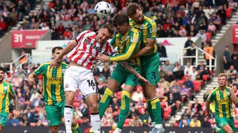 Nat Phillips and Chris Mepham leap to contest a header with Stoke's Ben Wilmot