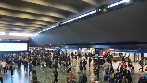 A view of the large advertising board at Euston train station in north London, which has been switched off by Network Rail with passengers viewed in the main hall