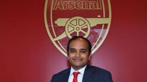 A picture of Tottenham CEO Vinai Venkatesham in front of the Arsenal badge when he was Arsenal managing director