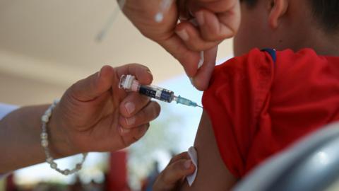A young boy gets an injection in his arm.