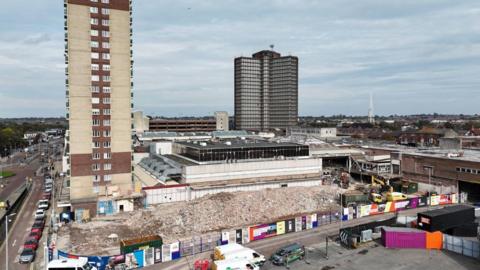 Aerial view of residential high-rise building Strand House towering over Bootle Strand shopping centre demolition site.