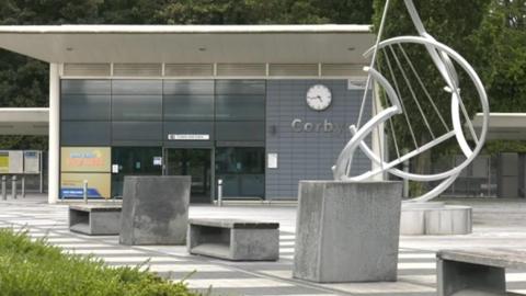 Modern metal and glass station building with modern sculpture outside