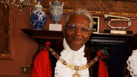 Dr Bharat Pankhania is wearing the ceremonial outfit in his role as mayor of Bath, a red and black robe, with white frilly ruff and gold chain.