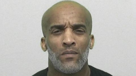 Mugshot of Mark Branker. His head is large and shaved and he has a neat grey beard. He is squinting slightly.