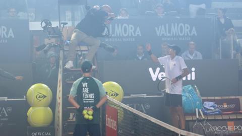 Spain's Rafael Jodar speaks with umpire Manuel Messina after smoke from the Coppa Italia final between Inter Milan and Lazio surrounds the court in his Italian Open quarter-final against Italy's Luciano Darderi