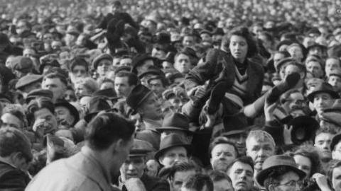 A young women is passed over the crowd in the crush at Bolton's ground in 1946.