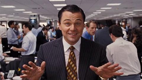 Leonardo DiCaprio looking at the camera in a busy office in The Wolf of Wall Street