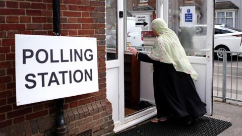 A woman walking into a polling station 