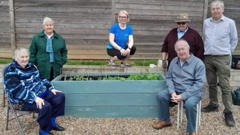 People with a wooden planter at Rushden Lakes