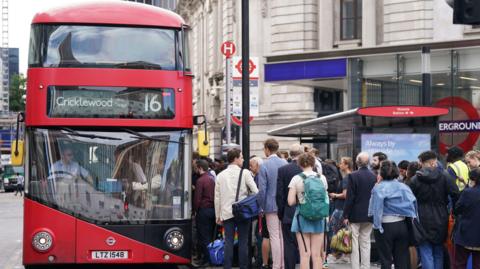 People waiting for a number 16 red London bus outside Victoria Station