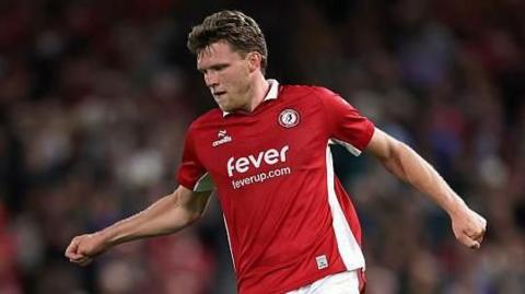 Rob Dickie in action for Bristol City wearing a red shirt, white shorts and red socks