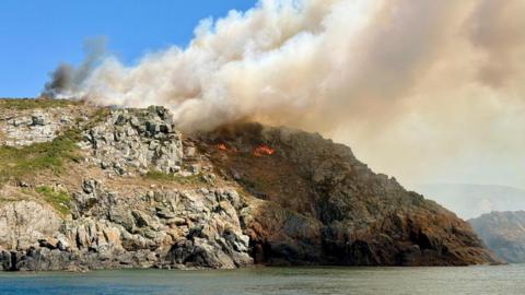 The south cliffs of Sark. You can see the orange flames and a considerable amount of smoke billowing.